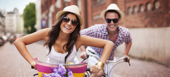 Get up to £50 discount! Young tourist couple riding bicycles.